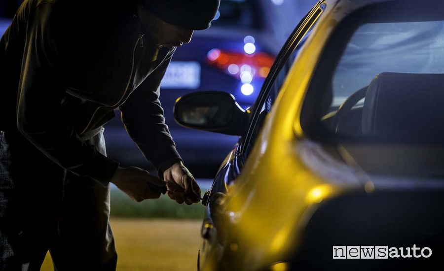 furto auto sera, ladro in azione che "spadina" una serratura