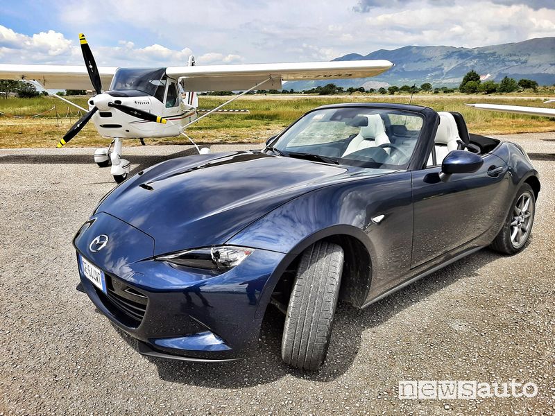 Vista di profillo Mazda MX-5 2021 a fianco di un aereo da turismo all'aero club di Celano