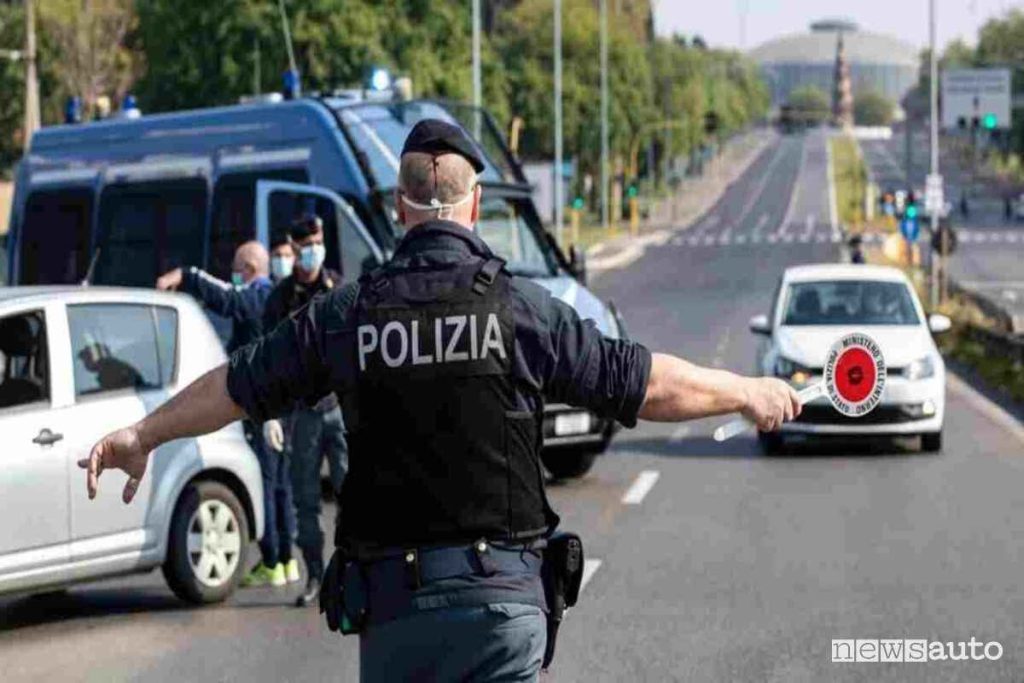 Un posto di blocco della Polizia mentre con la paletta di ordinanza ferma un'automobilista