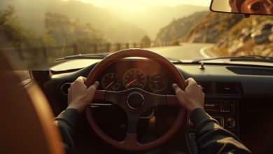 Guidare una youngtimer: primo piano di volante e cruscotto analogico di un'auto sportiva anni Novanta su strada di montagna