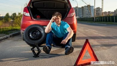 Ruotino di scorta e triangolo di emergenza accanto a un'auto ferma per una foratura